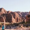 Back view group of anonymous hikers walking on dry terrain near Bungle Bungle range in Purnululu National Park on sunny day