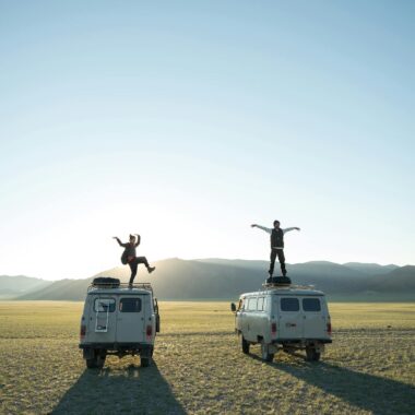 Travelers standing on vans in remote valley